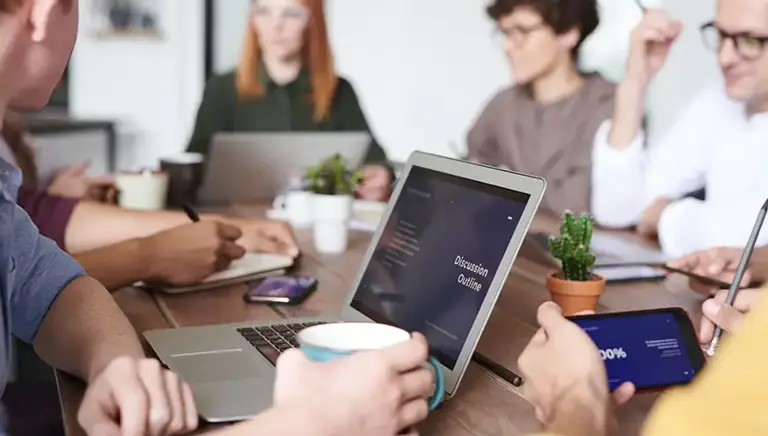 Team of office workers sat around a large conference table having a meeting